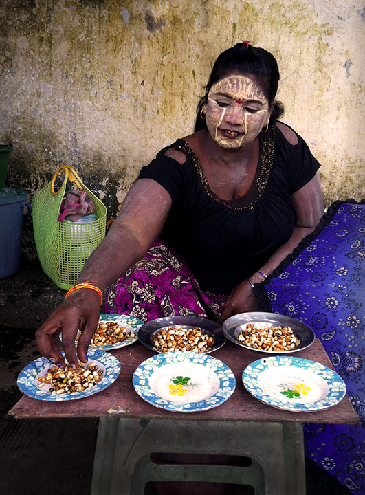 This woman is selling peanuts to feed the pidgeons near a Hindu Temple in Yangon, Burma.&nbsp; The face paint is called Thanaka...