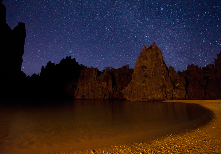 The light of my campfire illuminates the cliffs&nbsp;surrounding Hidden Beach near El Nido, Palawan. The milky way is visible...