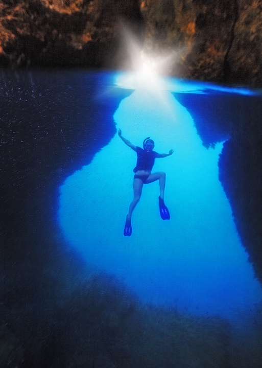 &nbsp;Swimming through a dark limestone cavern in the passage near Gam Island, Indonesia.