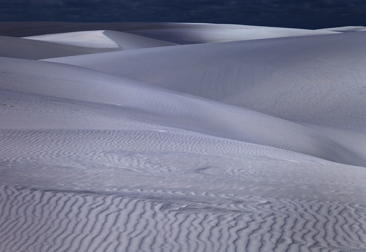 The shadows of tropical clouds cast long shadows over the sugar white dunes of the Lencois Maranhenses.