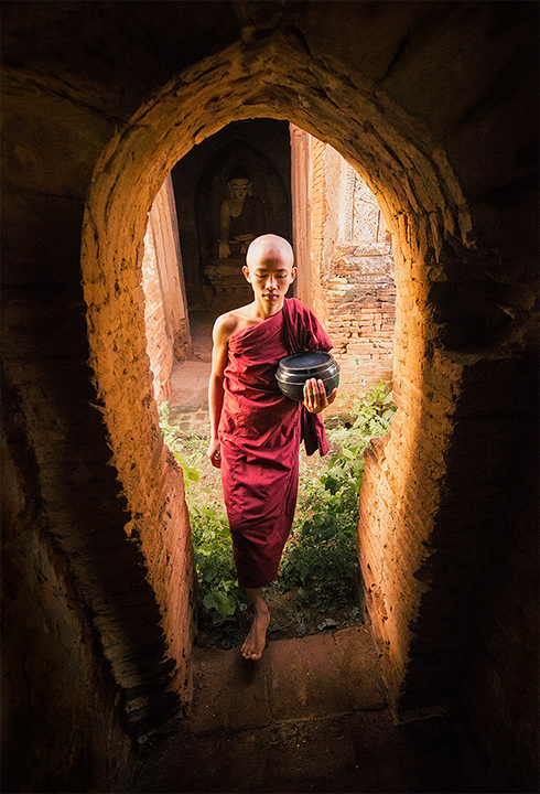 A young monk carrying morning alms back to the monastery.