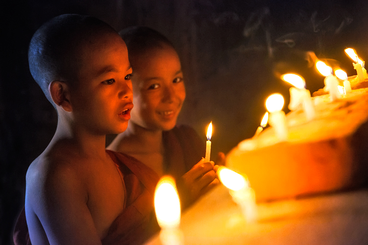 Lighting candles under the Buddha of an ancient temple.