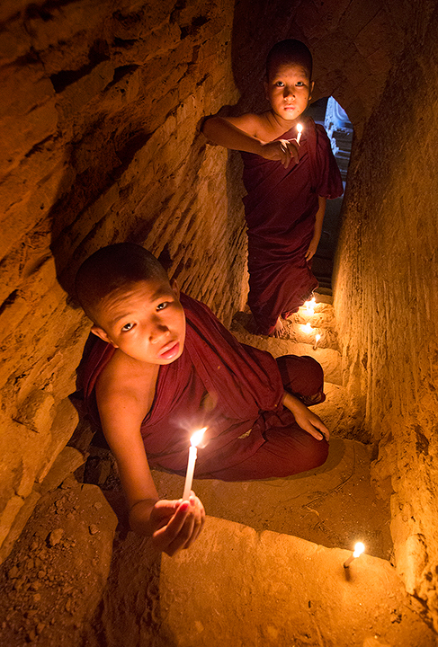 Illuminating the Stairway. Monks place candles in a dark stairway in preparation for anight festival at the temple.