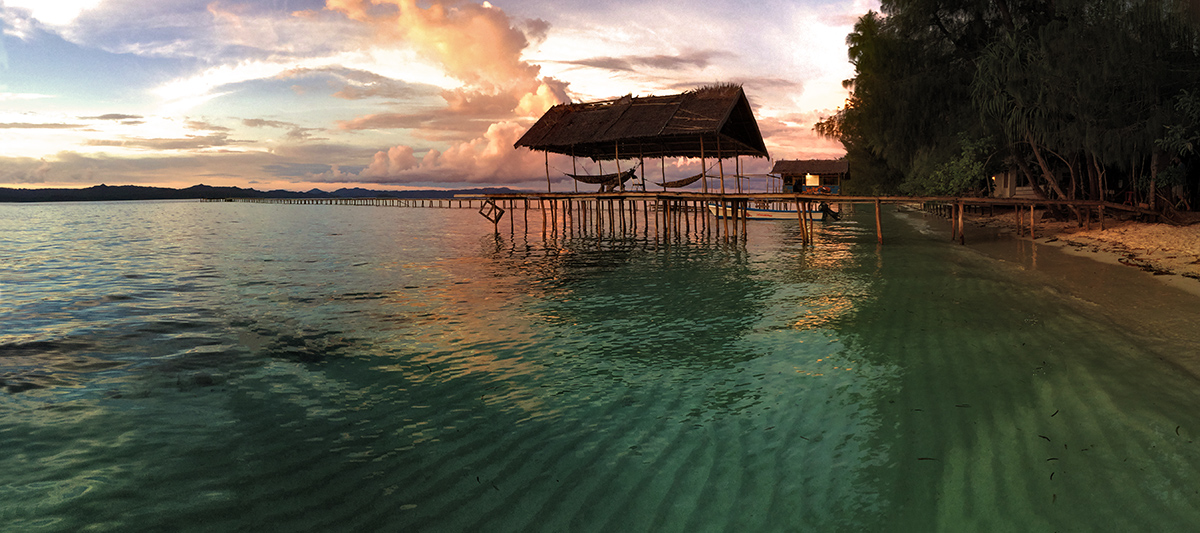 Yengkoranu Homestay Sunset Sunset over the beach and hammock deck of the Yengkoranu Homestay in Raja Ampat, Indonesia. One of the last wild and undiscovered...