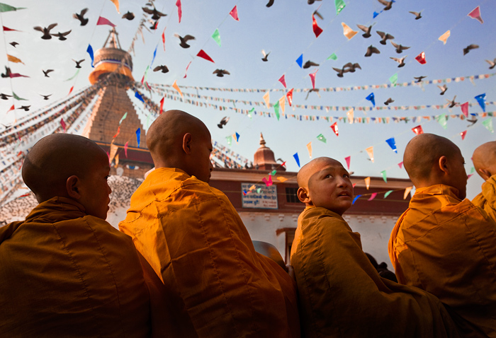 Enchanted Young monks at the famous Bodhnath Stupa watch pidgeons scatter overhead as the ceremonial drums begin.
