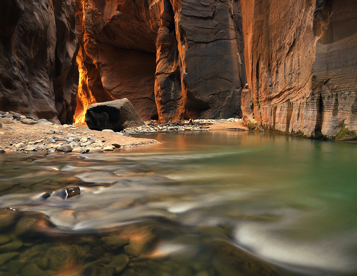 Sunlight filters down through massive canyon walls to illuminate a sheltered bend of the Virgin River.